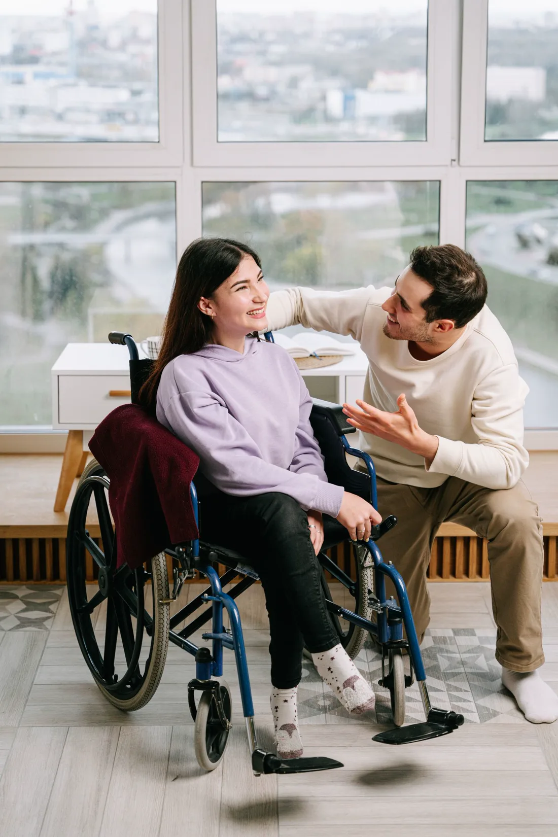 Two adults sharing a warm conversation at home, including a wheelchair user